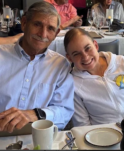 Kelly with her father, smiling together at a restaurant